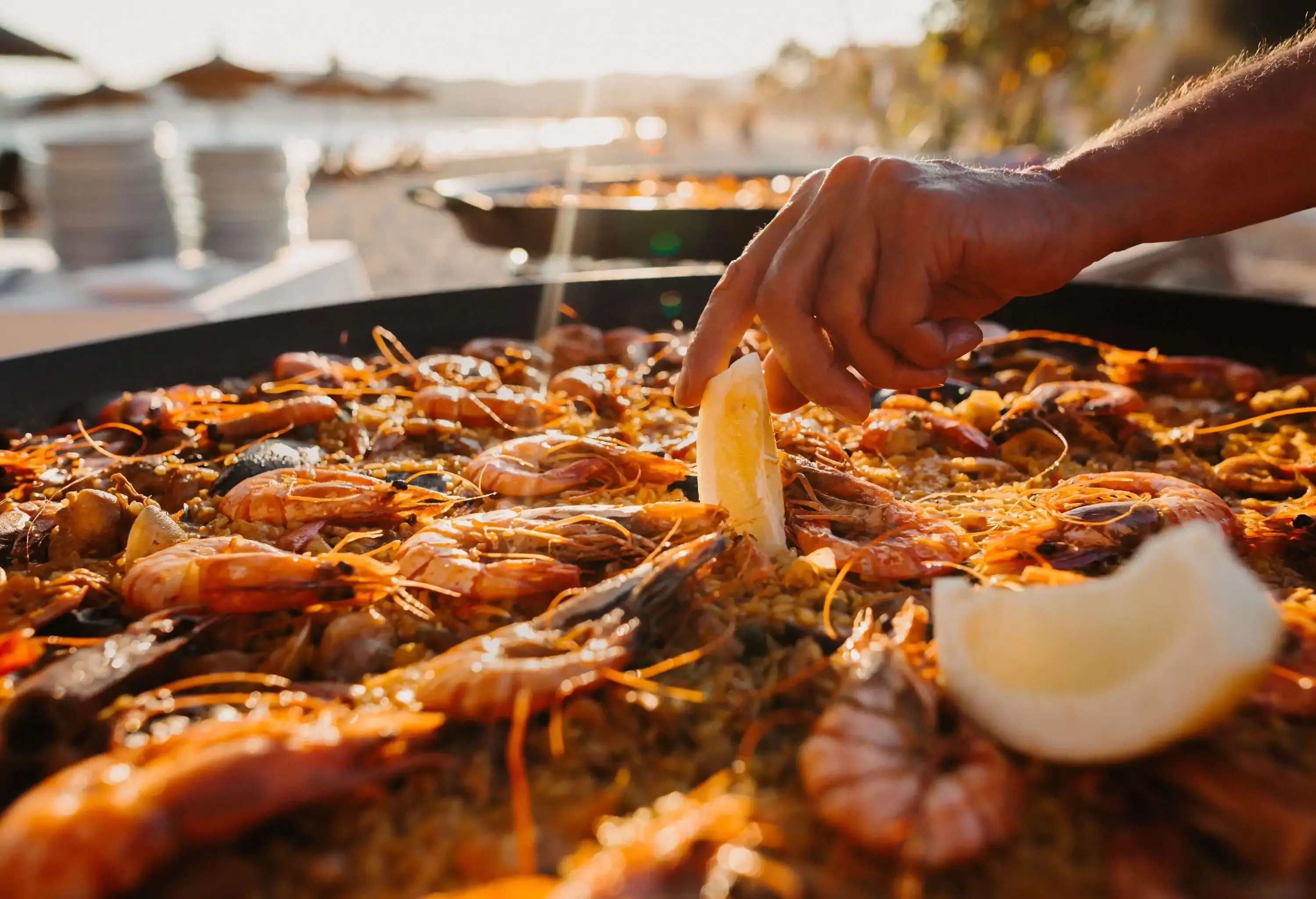 A pan of seafood paella garnished with lemon wedges.