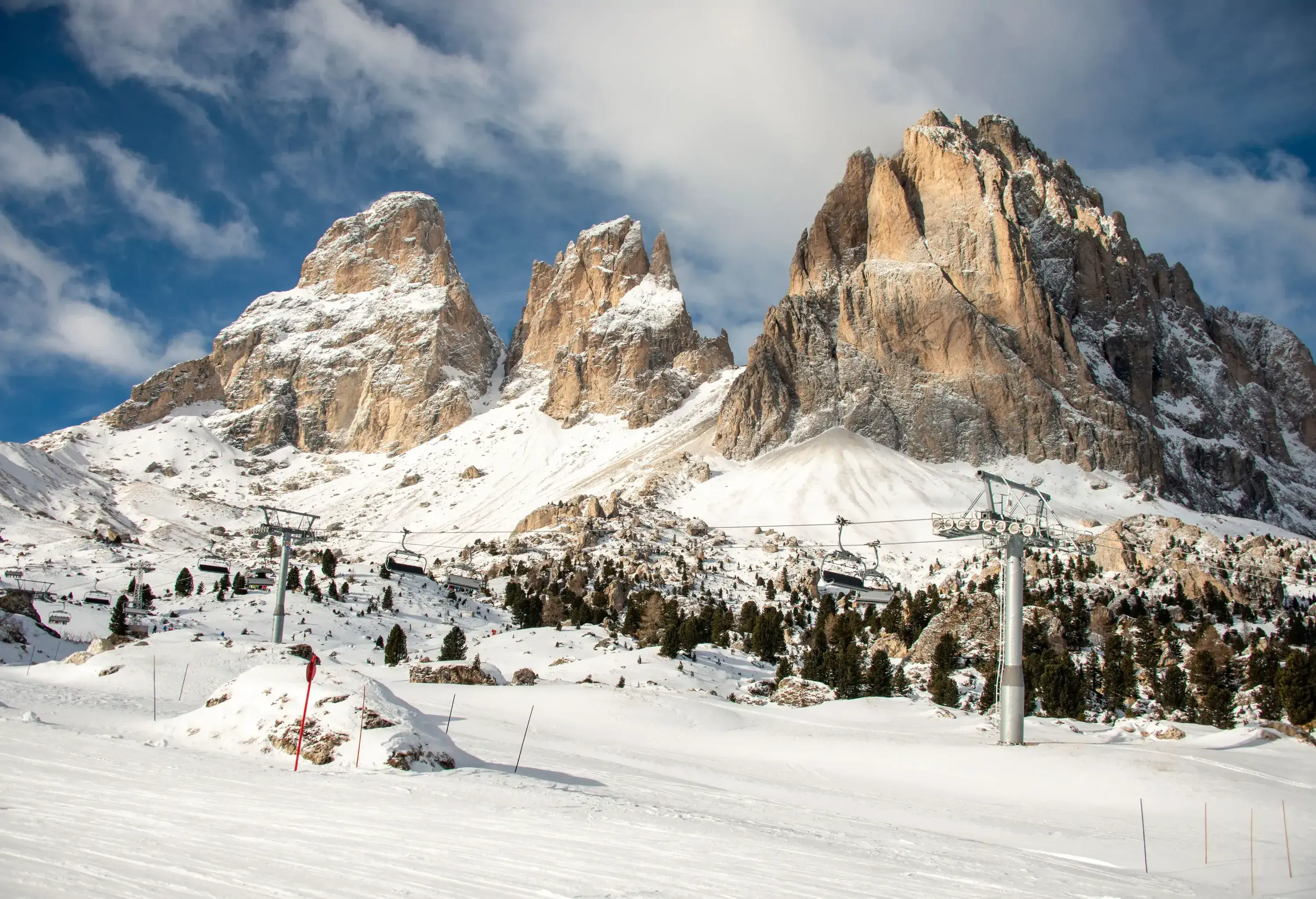 Ski towers connecting ski lifts on a snowy plain with three mountain peaks in the distance.