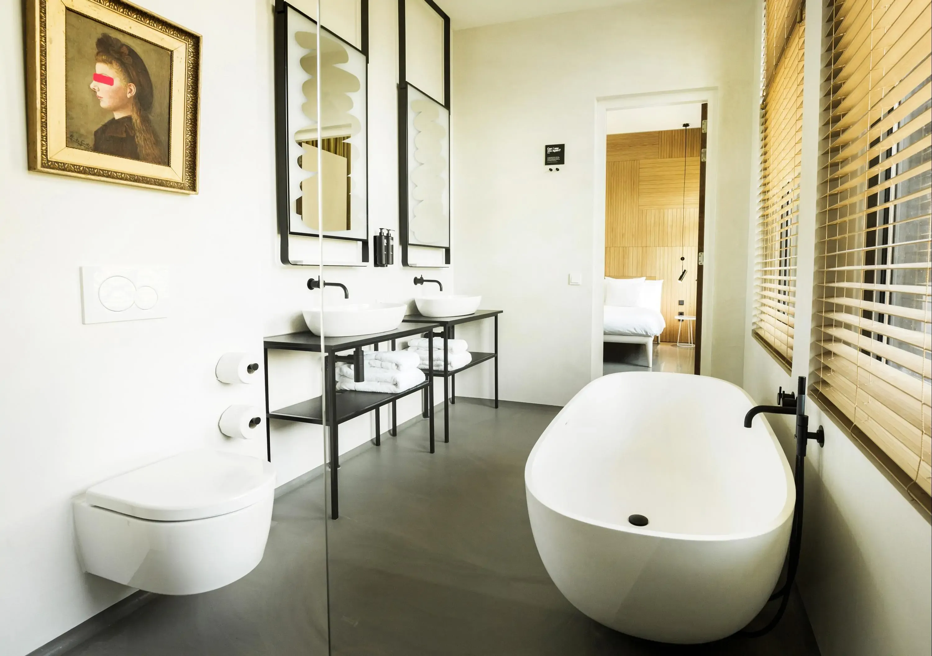 A minimalist luxury hotel bathroom with rolltop bathtub overlooking bedroom