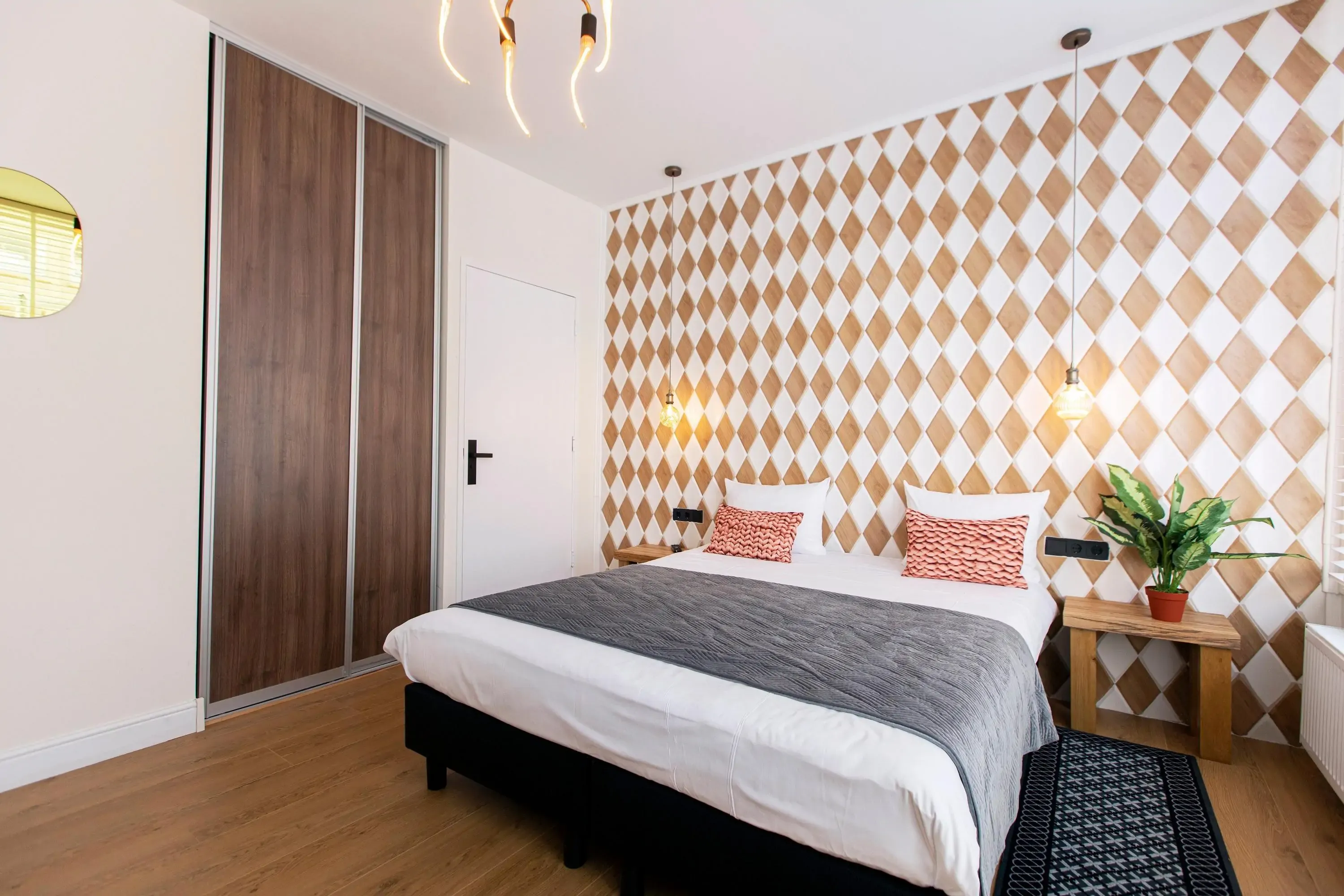 Modern minimalist hotel room with a feature wall with gold and white harlequin tiles