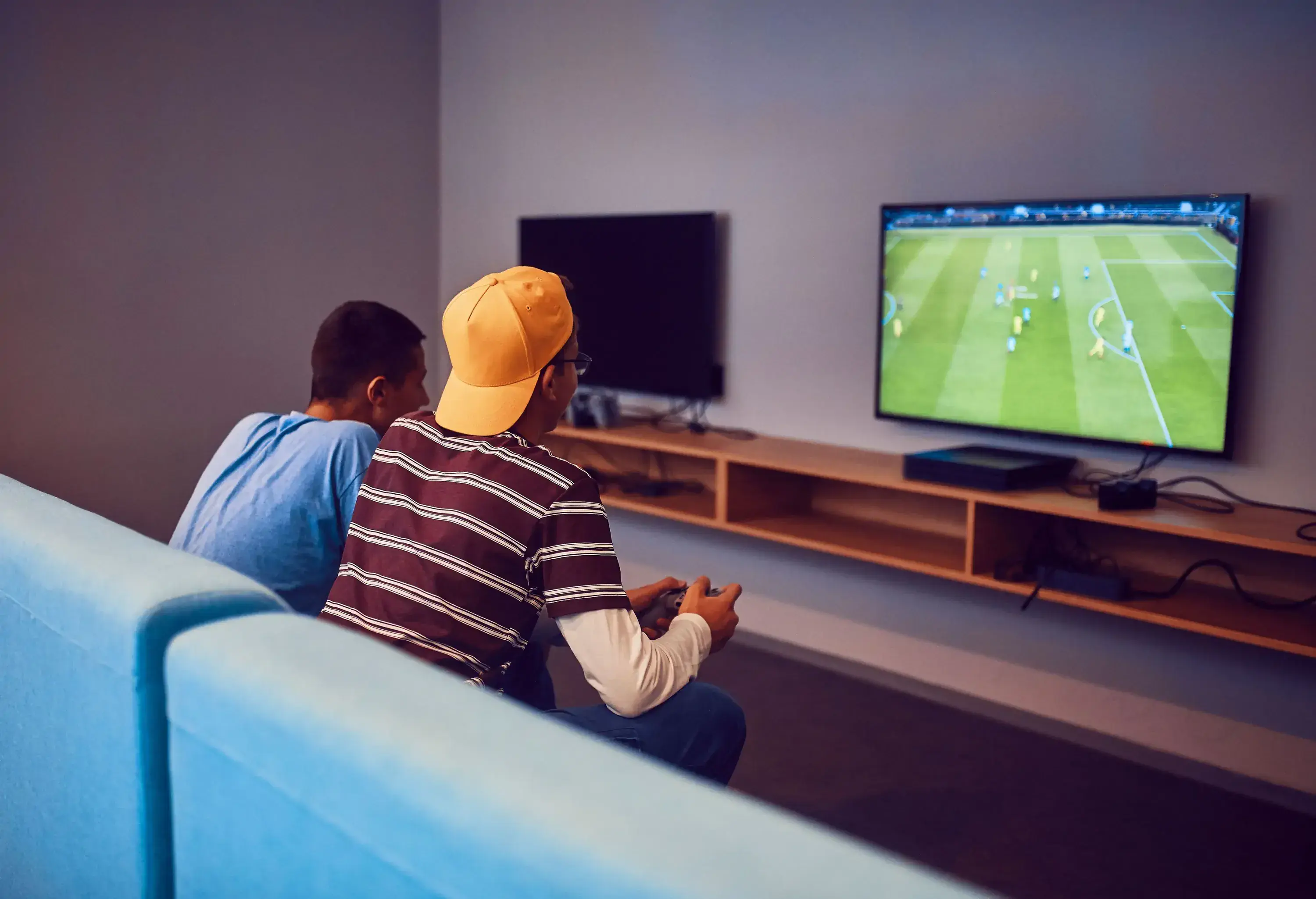 Two individuals sitting on a couch playing a video game on a TV.
